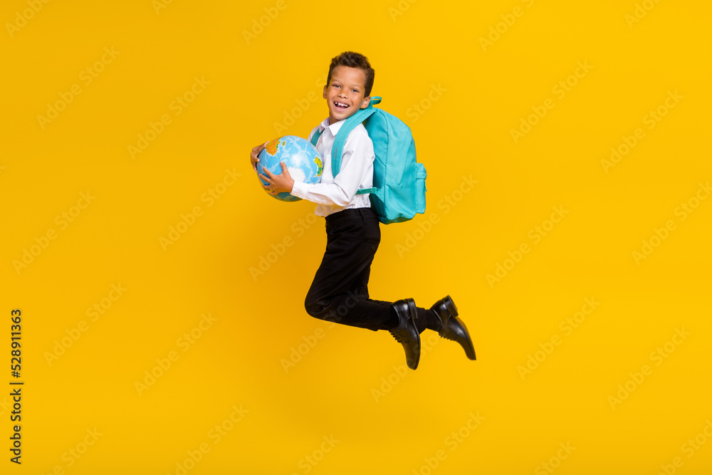 Full body portrait of crazy carefree little schoolboy jump hands hold planet earth globe isolated on yellow color background