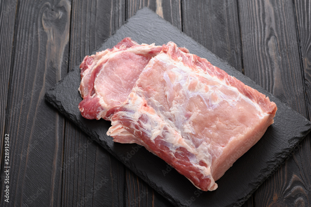 A large piece of pork loin on a rustic dark background. A large piece of pork loin on a rustic dark background.