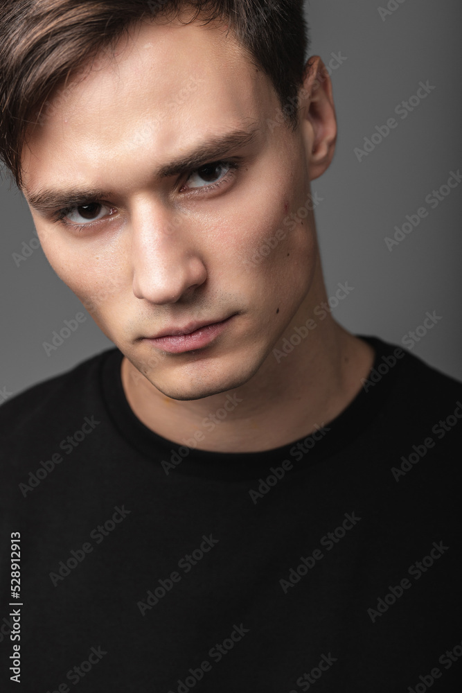 A guy of model appearance in black clothes poses on a gray studio background. Male fashion portrait A guy of model appearance in black clothes poses on a gray studio background. Male fashion portrait