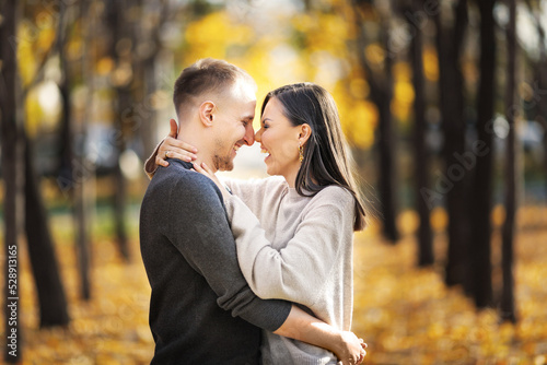 Young happy couple in love on a date laughing and hugging in autumn park.