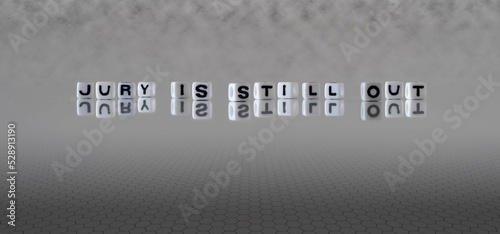 jury is still out word or concept represented by black and white letter cubes on a grey horizon background stretching to infinity