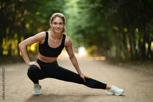 Cheerful active young lady enjoying workout at public park