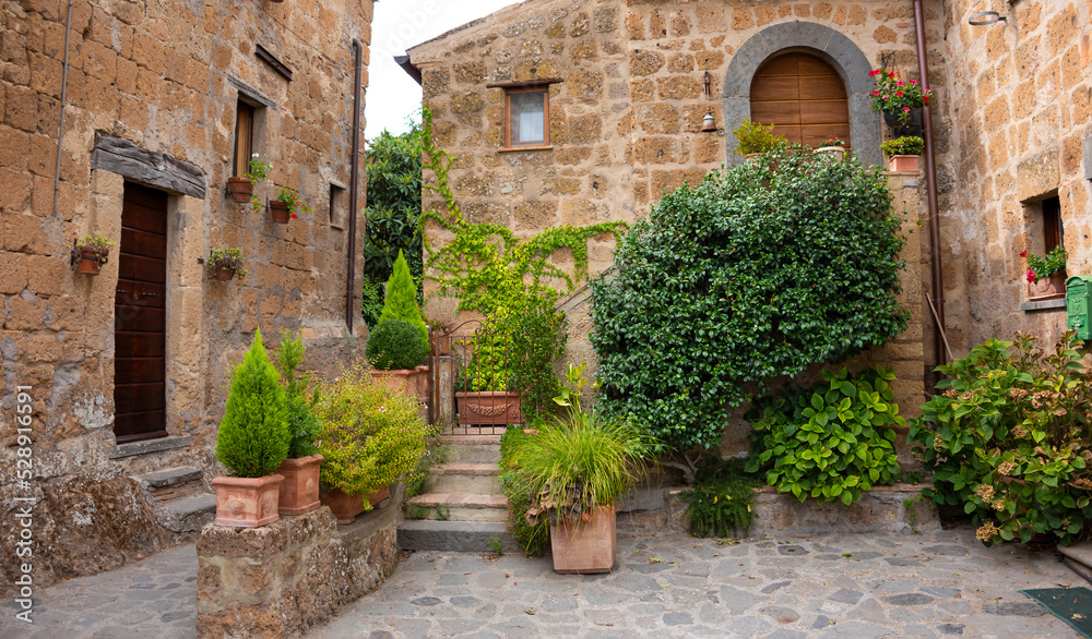 Picturesque courtyard in medieval town in Tuscany, Italy. Old stone walls and plants