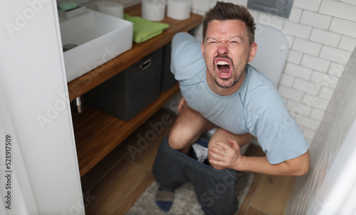 Man suffering from hemorrhoids screams on toilet in toilet