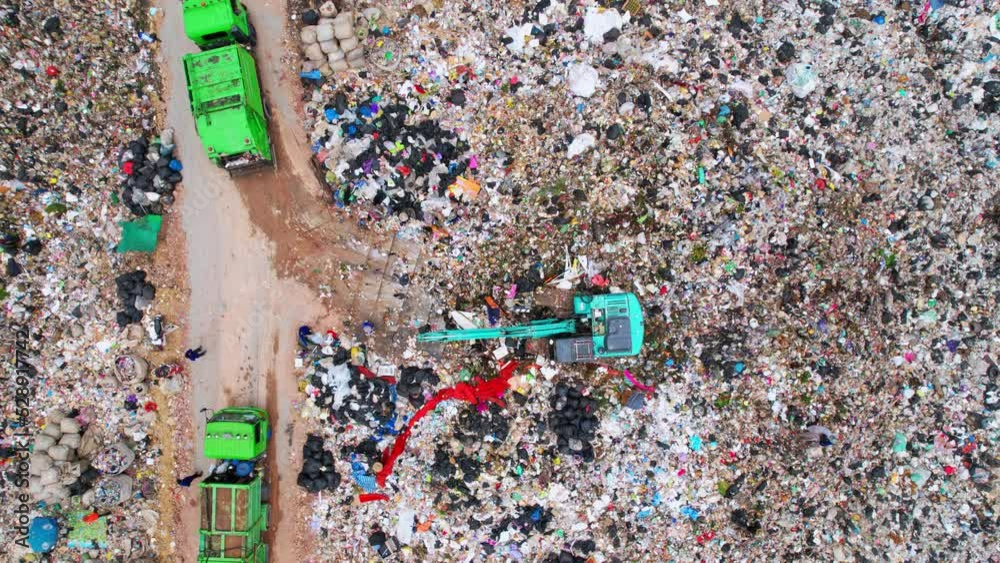 Drone flying over a huge pile of trash. workers sort out the garbage in ...