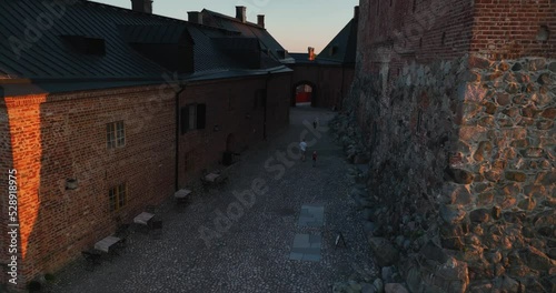 Aerial view around father and kids exploring the Hame castle, summer sunset in Hameenlinna, Finland - circling, drone shot photo