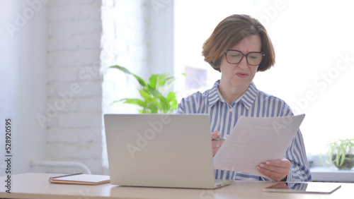 Senior Woman Upset while Reading Documents in Office