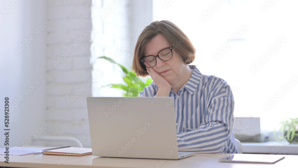Senior Woman Sleeping While Sitting in Office with Laptop Senior Woman Sleeping While Sitting in Office with Laptop