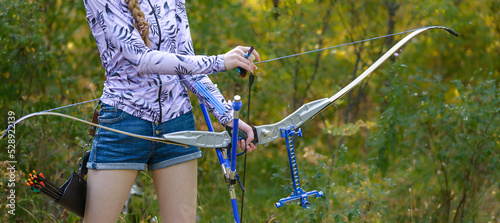 professional archer shooting with modern longbow in forest