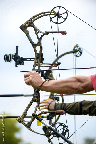 professional archer shooting with modern longbow in forest