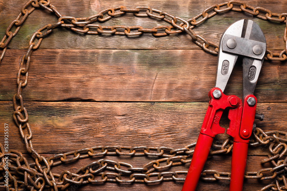 Bolt cutters rebar shears and iron chain on brown wooden workbench
