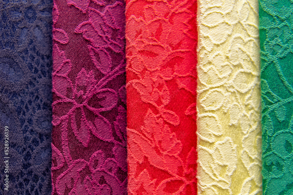 Samples of colored brocade fabrics in selective focus. A large assortment of high-quality and fashionable fabrics, a choice of textiles in the fabric store. Samples of colored brocade fabrics in selective focus. A large assortment of high-quality and fashionable fabrics, a choice of textiles in the fabric store.