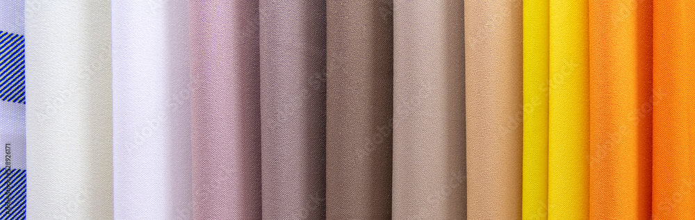 Fototapeta premium Samples of colored gabardine fabrics in selective focus. A large assortment of high-quality and fashionable fabrics, a choice of textiles in the fabric store.