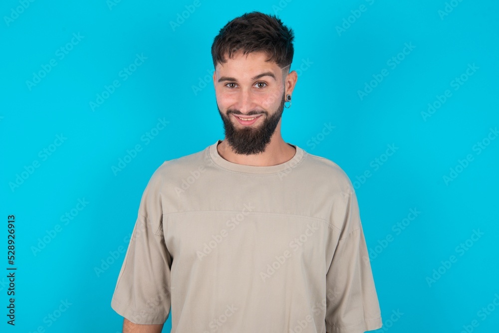 Fototapeta premium bearded caucasian man wearing casual T-shirt over blue background with nice beaming smile pleased expression. Positive emotions concept