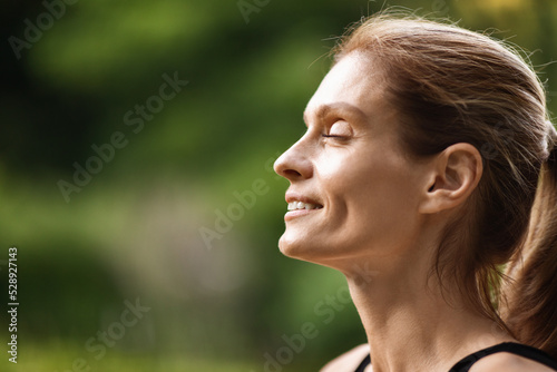Peaceful young lady smiling with closed eyes while meditating