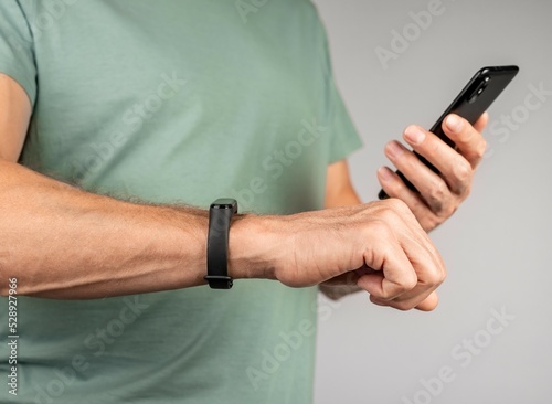 Man looking at fitness tracker app at phone and checking sports results  health metrics. Tool for daily activity monitoring. Steps number counting  heart rate  sleep patterns tracking.