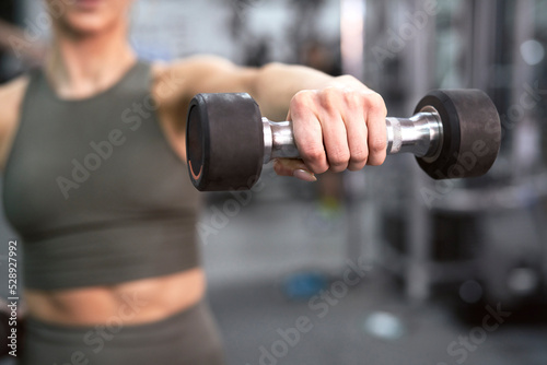 Close up of dumbbell held by unrecognizable sportsperson at the gym