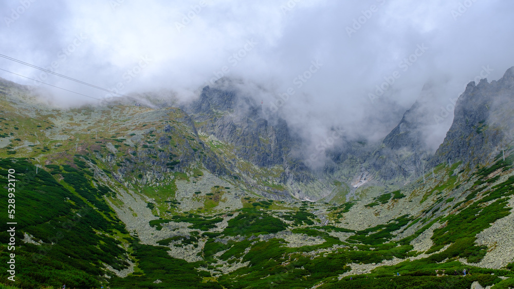 low hanging storm clouds and fog in the mountains on a summer day. blue haze in mountain valleys.