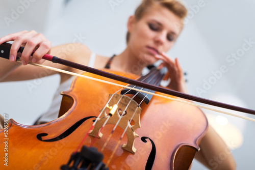 Foto Young woman playing cello on the concert at night