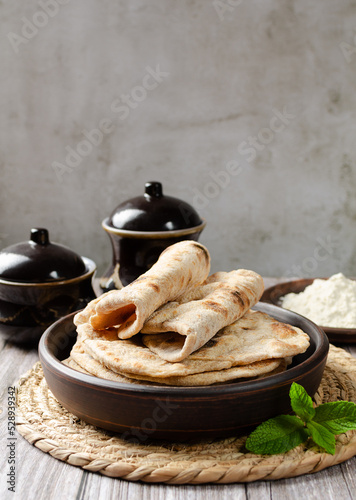 Homemade Chapati Roti Flatbread with greens and garlic on grey background. Freshly baked indian street food. Copy space for text