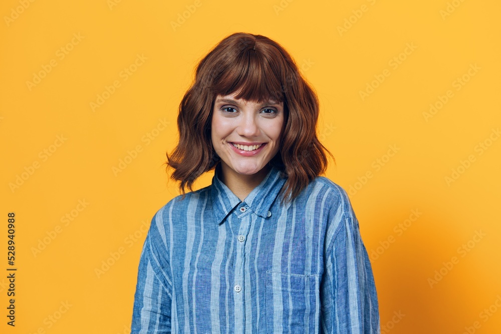 horizontal photo on a yellow background of a cute, happy woman in a blue shirt horizontal photo on a yellow background of a cute, happy woman in a blue shirt