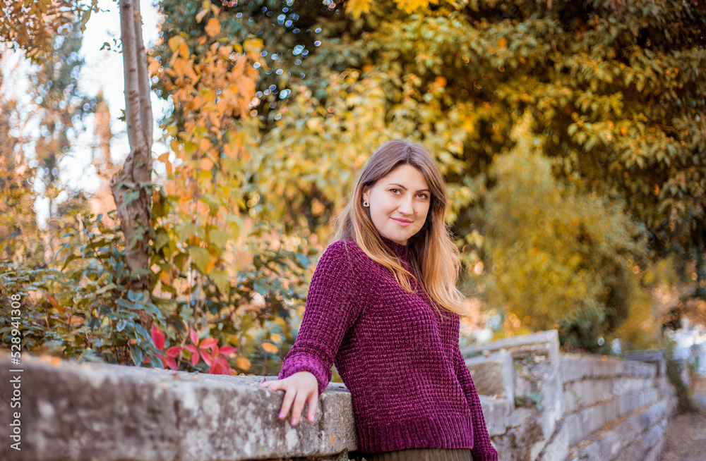 Fototapeta premium Portrait of beautiful woman in burgundy sweater on a background of autumn tree. 