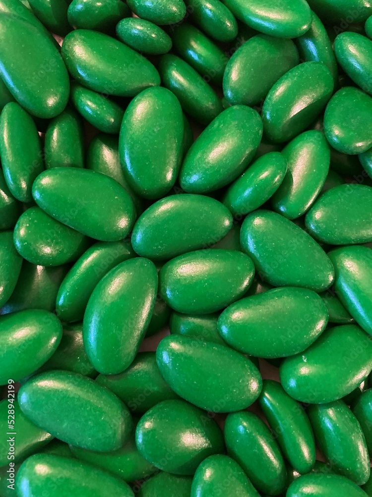 Close up of green drage. Green background with green dragees. Green chocolate bonbon with almond flavour. Close up of green drage. Green background with green dragees. Green chocolate bonbon with almond flavour.