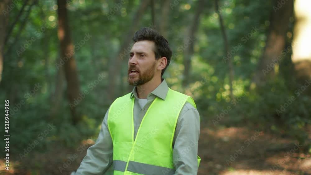 Middle aged man volunteer wearing bright green vest searching missed person in wild forest, shouting in wood Middle aged man volunteer wearing bright green vest searching missed person in wild forest, shouting in wood