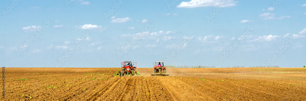 Fototapeta premium Farmers with tractors sowing on agricultural fields on sunny spring day 