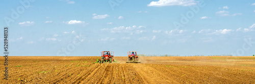Farmers with tractors sowing on agricultural fields on sunny spring day 