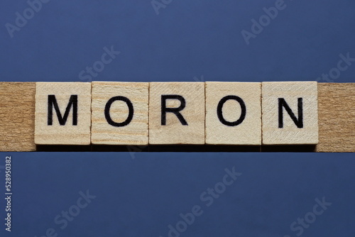 text the word moron from brown wooden small letters on a black table