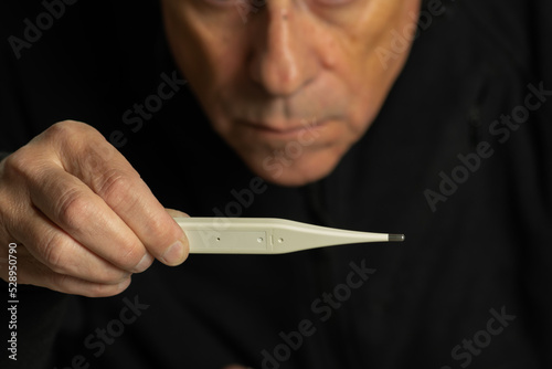 Partial view of a person looking at a body temperature thermometer