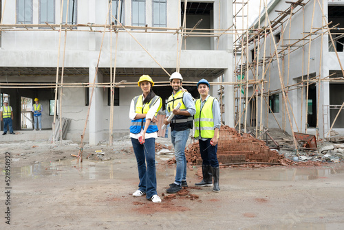 Construction engineer and architect team discuss housing development project at construction site. Contractor manager inspecting residential building estate infrastructure. Men, woman at work outdoor. © Nassorn