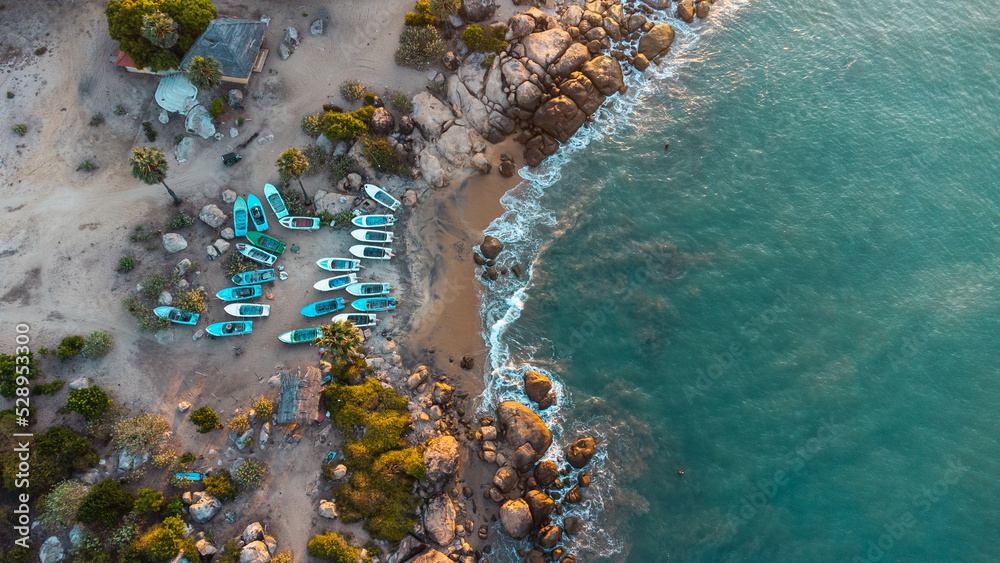 Ocean tropical landscape, rocky coast with fishing boats, drone shot, water and beach.