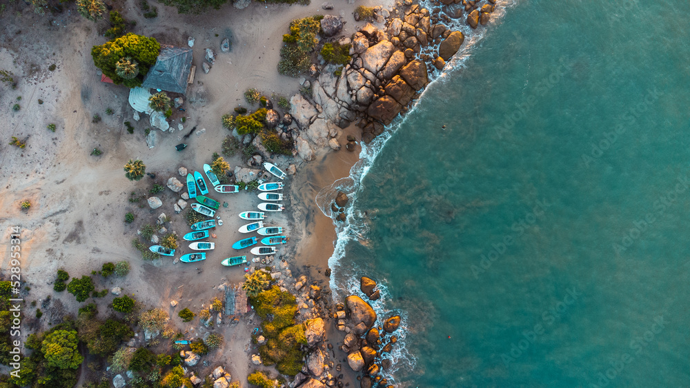 Ocean tropical landscape, rocky coast with fishing boats, drone shot, water and beach.