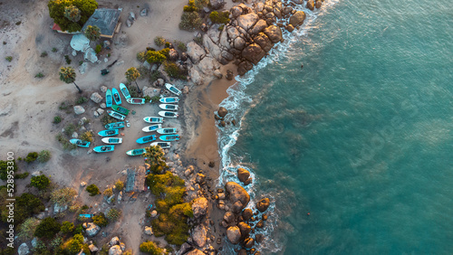 Ocean tropical landscape, rocky coast with fishing boats, drone shot, water and beach.