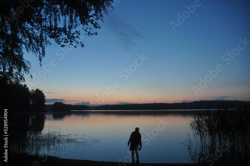 girl at sunset in the evening on the shore of the lake in the forest posing