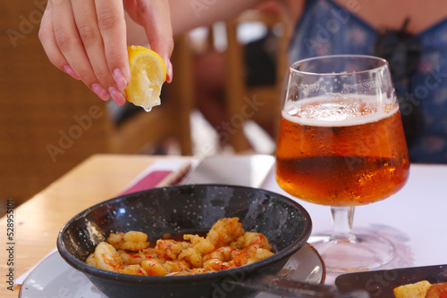 fried shrimps with lemon slice, garlic sauce aioli and tomato ketchup frying pan close up photo with beer