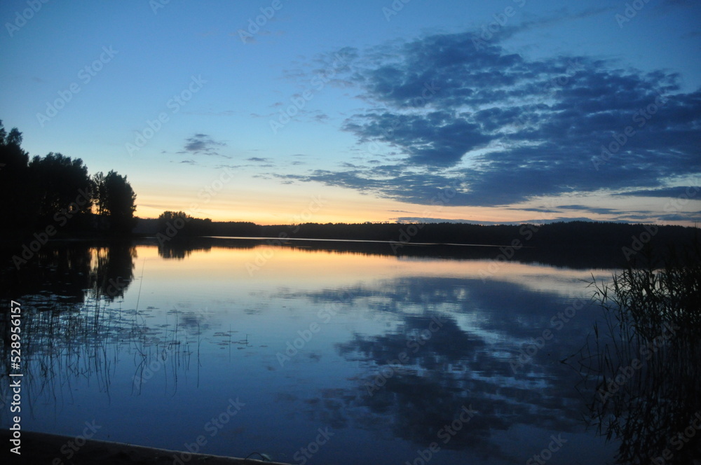 lake in the forest sunset, reeds around, smooth water reflection of trees