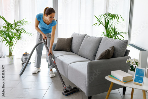 Woman vacuuming the floor at home