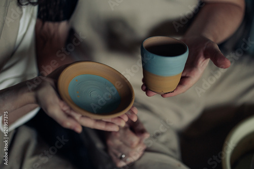 Two persons hold handmade earthenware in their hands.