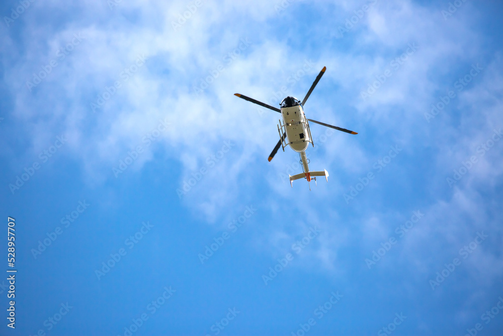 Fototapeta premium Helicopter close-up against the sky. Rescue helicopter flies in the sky with clouds.
