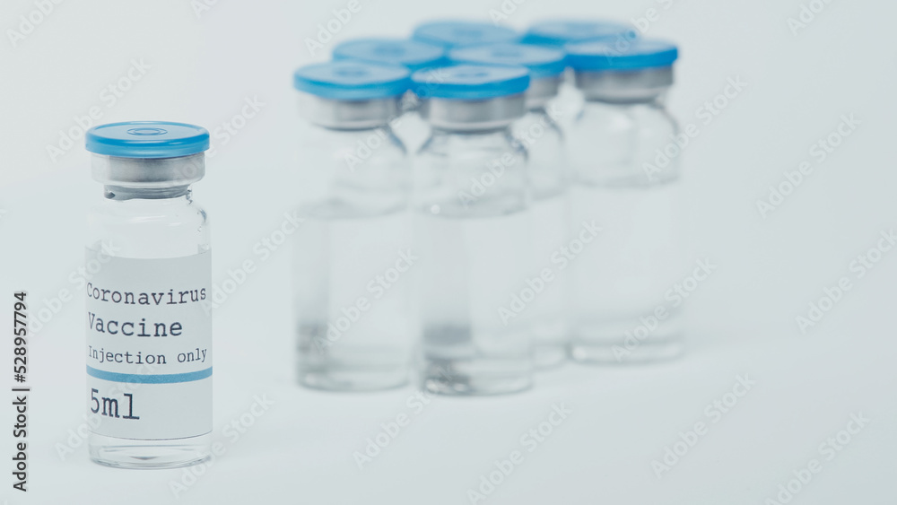 close up of glass bottles with coronavirus vaccine lettering isolated on white. close up of glass bottles with coronavirus vaccine lettering isolated on white.