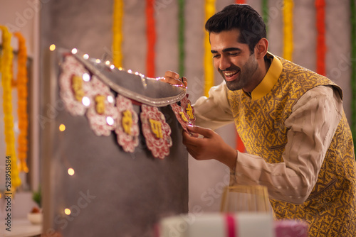 Young man in traditional outfit decorating office during Diwali celebration photo