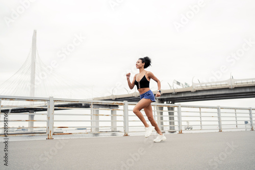 Millennial runner woman running fast sports workout in the city. Fitness tracker on the arm.