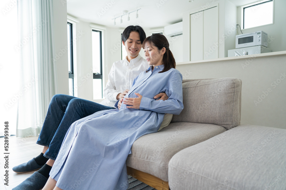 Fototapeta premium 自宅で笑顔でお腹をさする日本人夫婦