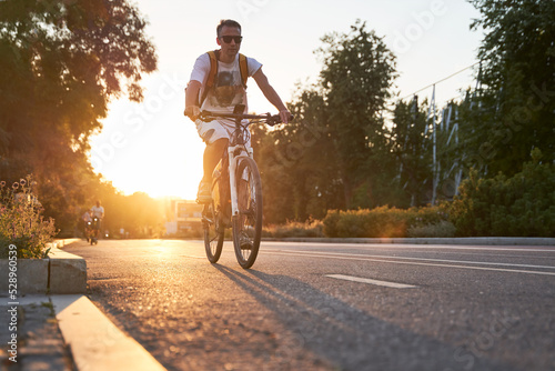 Man is riding on bicycle on the street on the sunset.