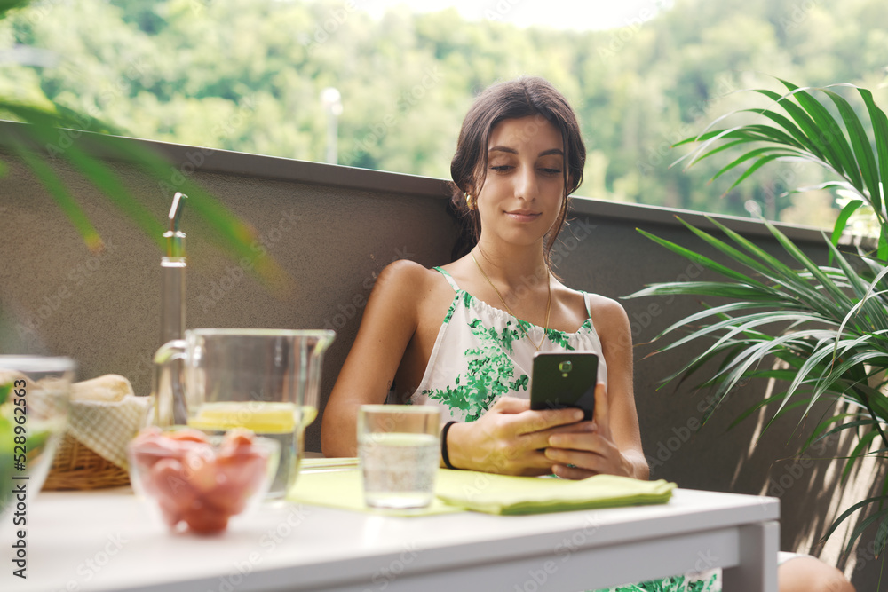 Woman sitting on the balcony and using her smartphone Woman sitting on the balcony and using her smartphone