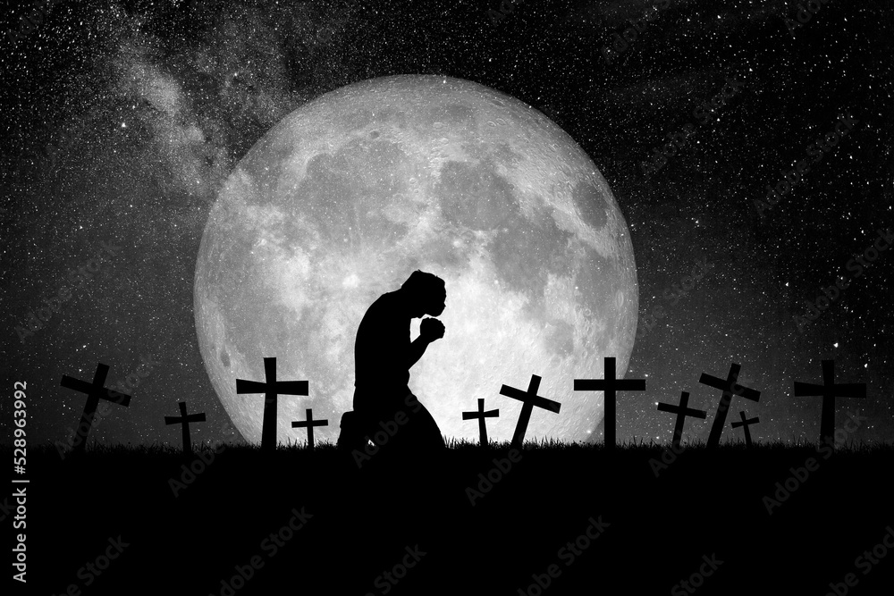 The idea of ​​praying for peace to reduce the loss of war. A Christian man prays in a field with graves and moons.