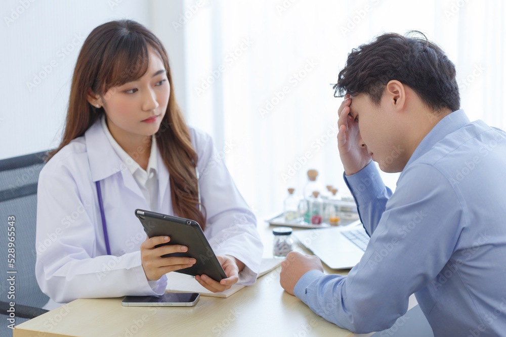 Female doctor and young male patient while consult and .explain. Doctor and patient sitting together at table in examination room. Female doctor and young male patient while consult and .explain. Doctor and patient sitting together at table in examination room.